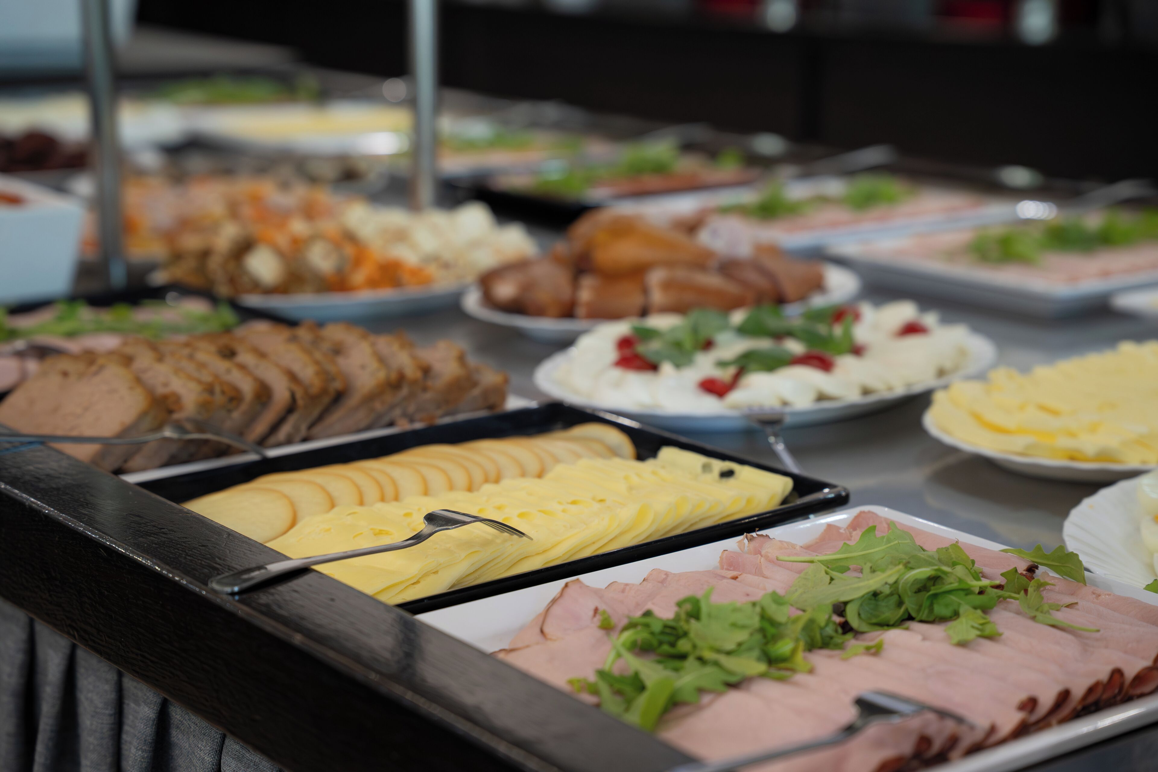 A buffet with various food items including sliced meats, cheeses, and salads.