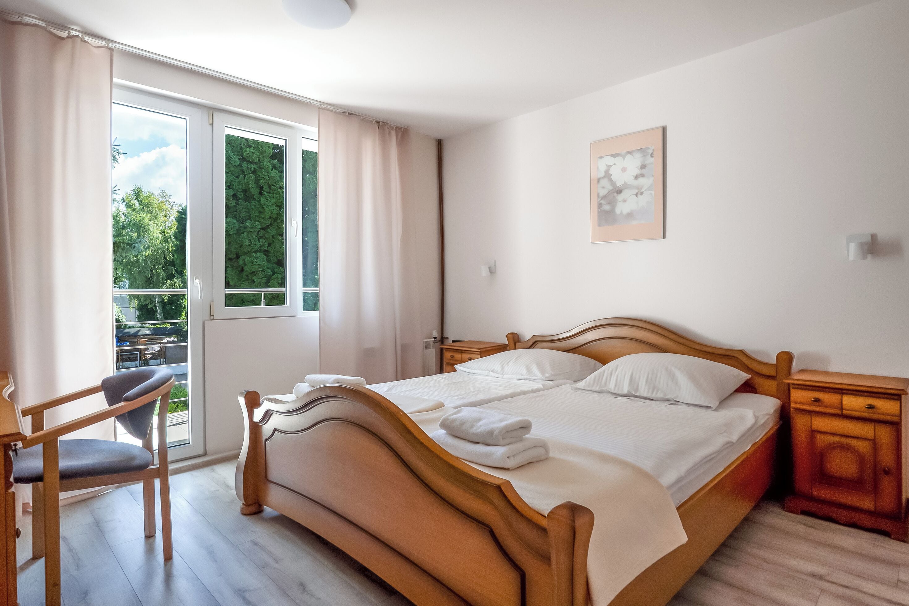 Una camera da letto con un letto, una sedia, un comodino e una finestra con tende.