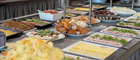 A buffet with various food items including meats, cheeses, and salads.