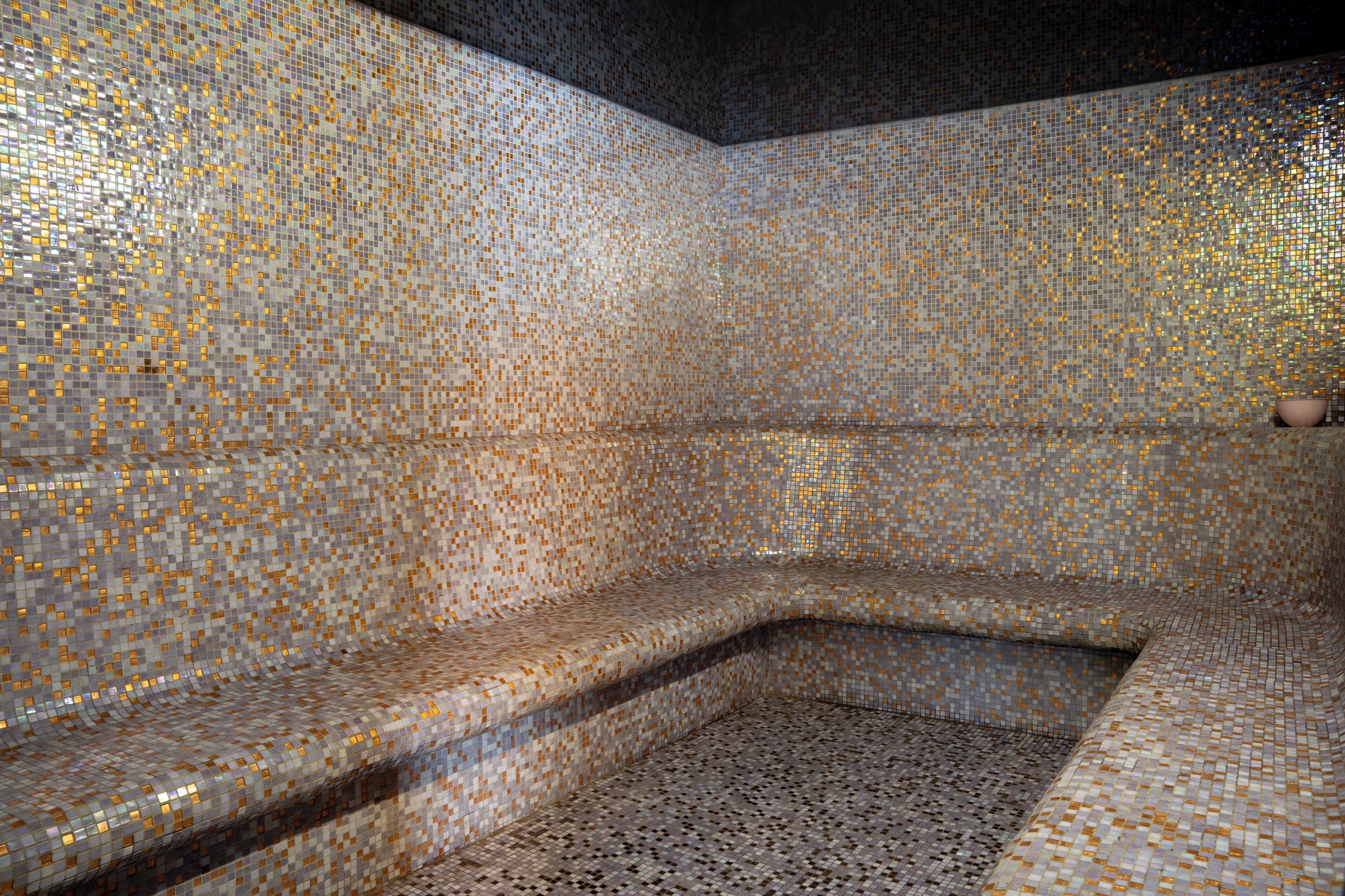 Una habitación con paredes de mosaicos y un banco.
