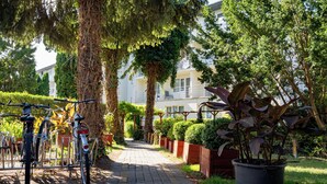 A paved pathway leading to a building with a bicycle rack and potted plants. - Graal Spa (Swinoujscie)