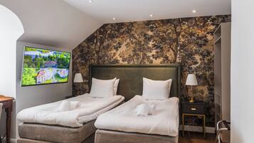 Quarto de hotel com duas camas, televisão na parede e papel de parede floral.
