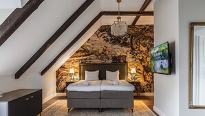 Een slaapkamer met een bed, een kroonluchter, een televisie en een muurschildering.