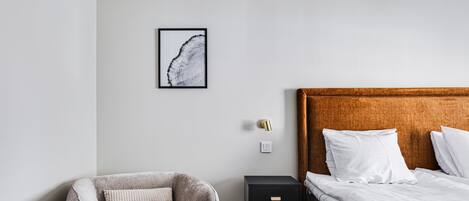 Une chambre à coucher comprenant un lit, une chaise, une table de chevet et un interrupteur fixé au mur.