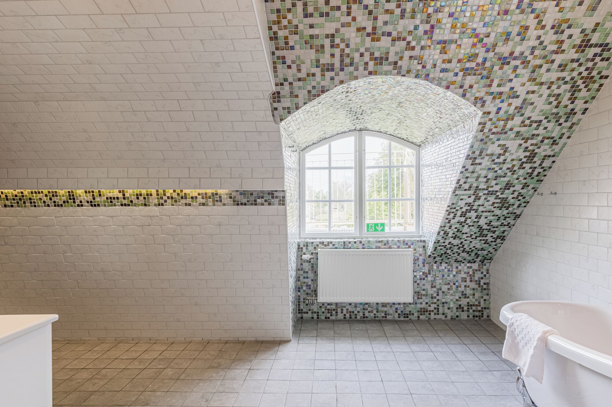 A bathroom with a tiled floor, a window, and a bathtub.