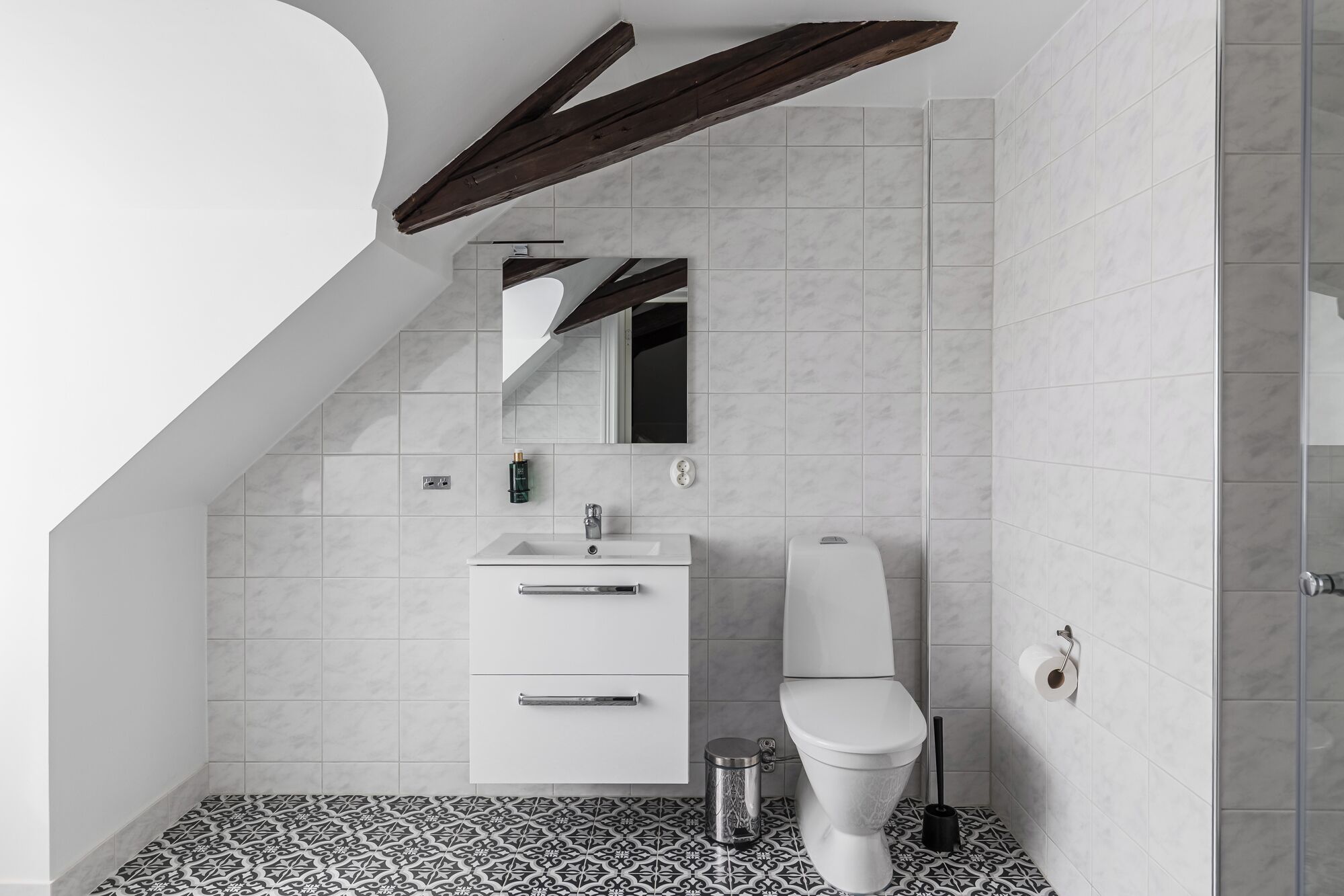 Casa de banho moderna com lavatório, espelho e sanita brancos.