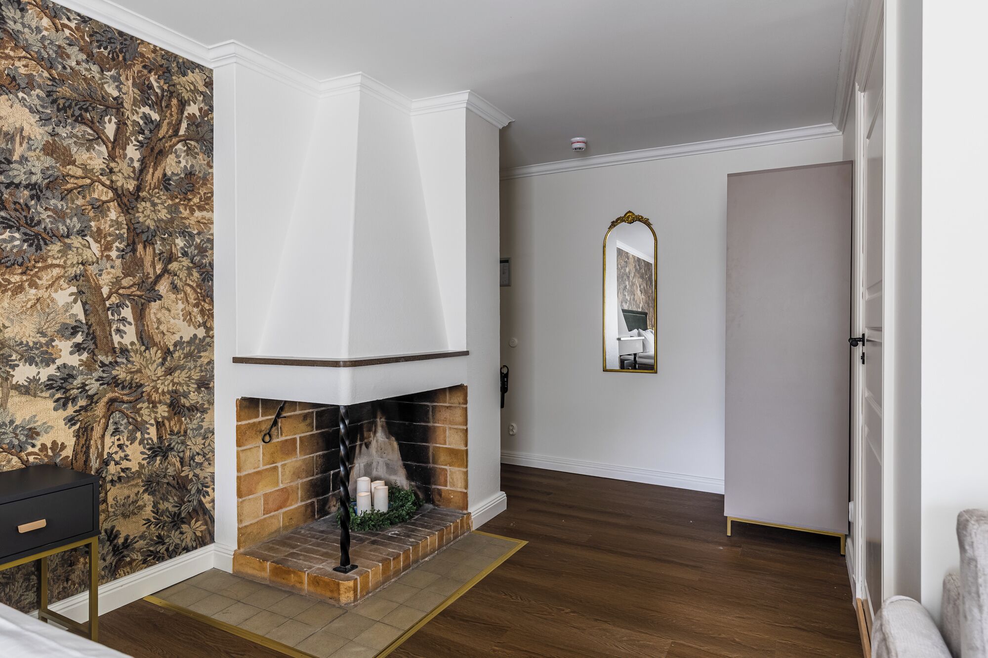 A room with a fireplace, a mirror, and a door.
