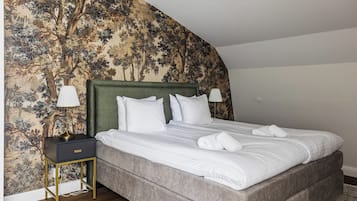 Quarto com uma cama grande, uma mesa de cabeceira com abajur e uma parede com padrão floral.