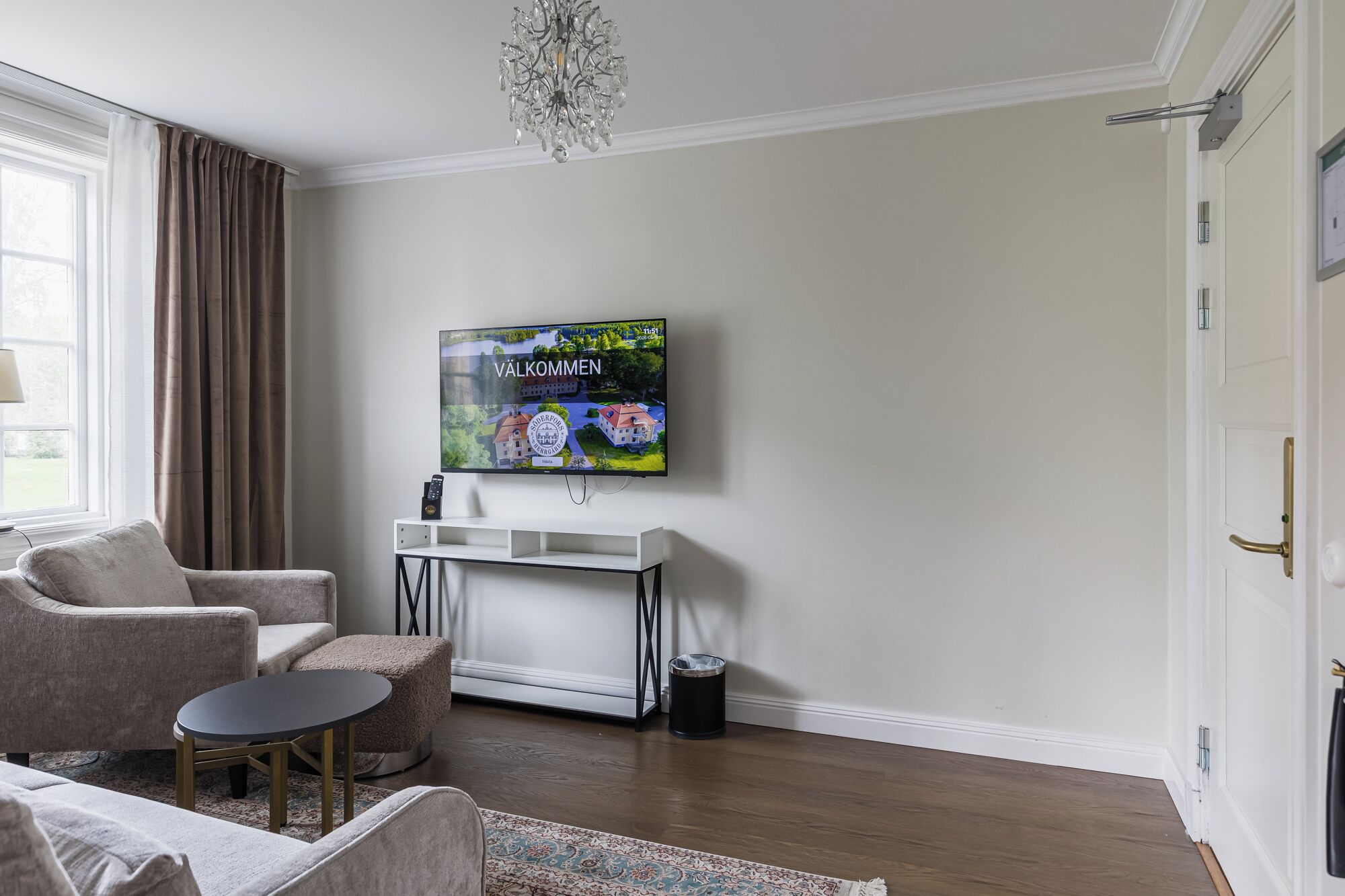 A living room with a TV, sofa, armchair, coffee table, and a rug.