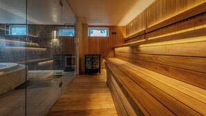 Een sauna met houten banken, een glazen wand en een vloer van natuursteen.