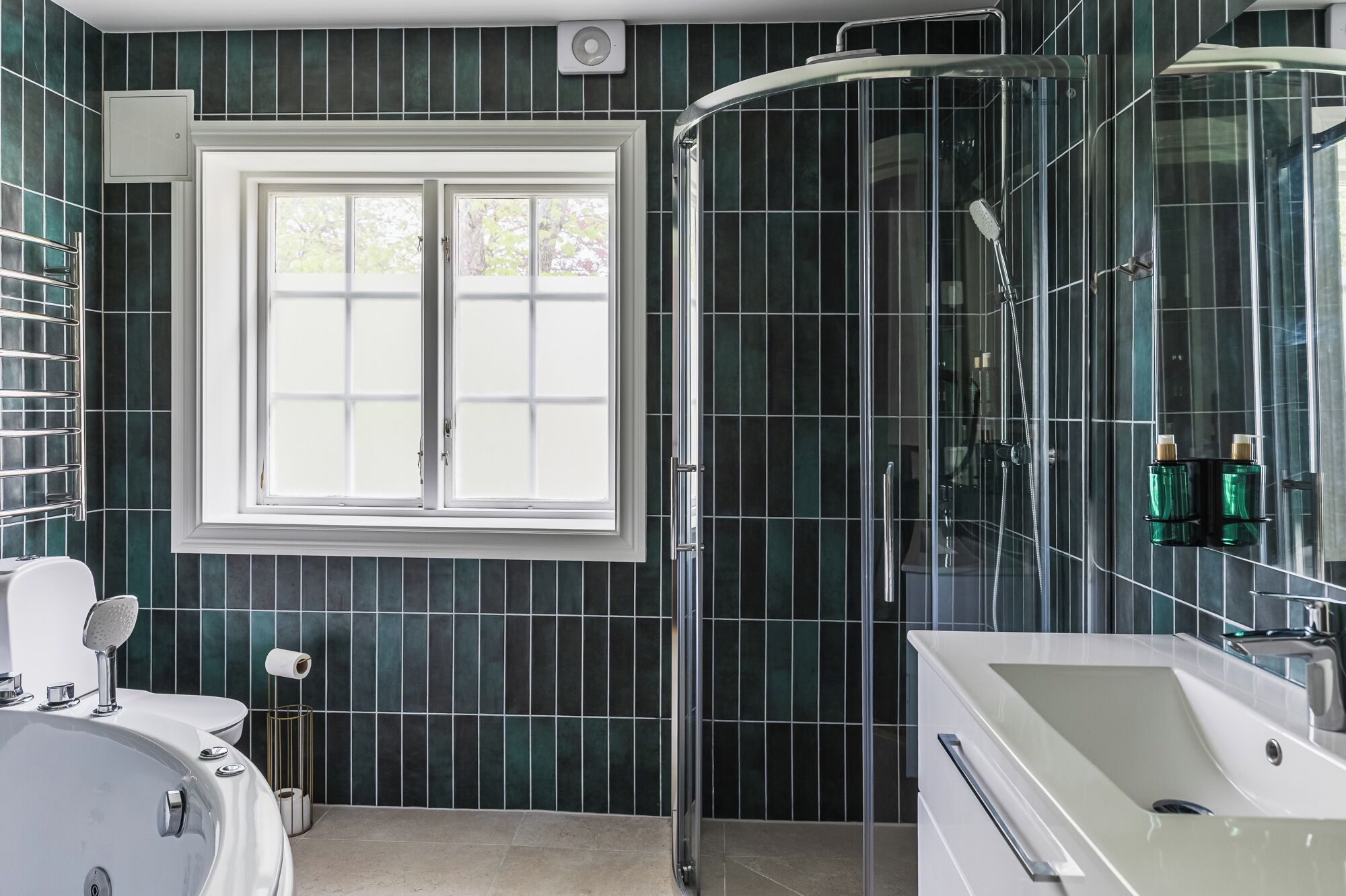 A modern bathroom with a glass shower enclosure, a large mirror, and a white sink.