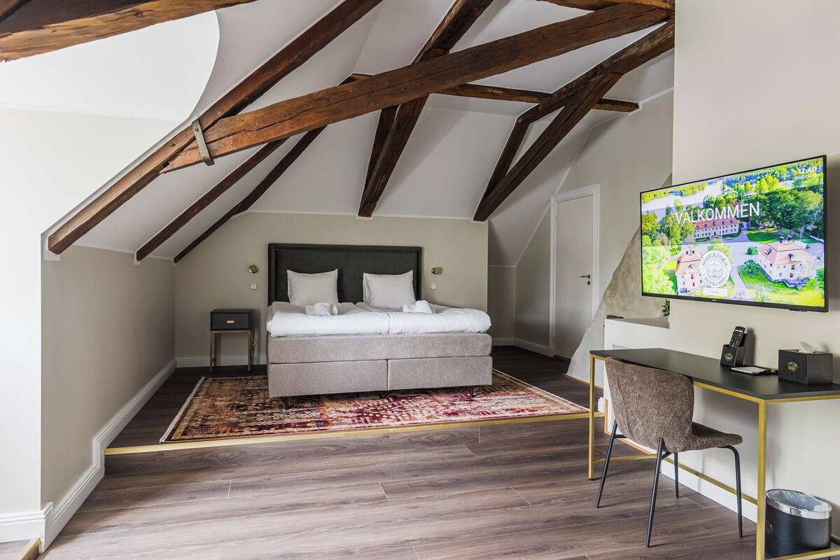 Un dormitorio con una cama, un escritorio y un televisor mostrando un mapa.