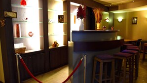 Zona de recepción con mostrador, taburetes y una barrera de cuerda roja.