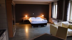 Una habitación de hotel con una cama, lámparas de noche, un sofá y una mesa.