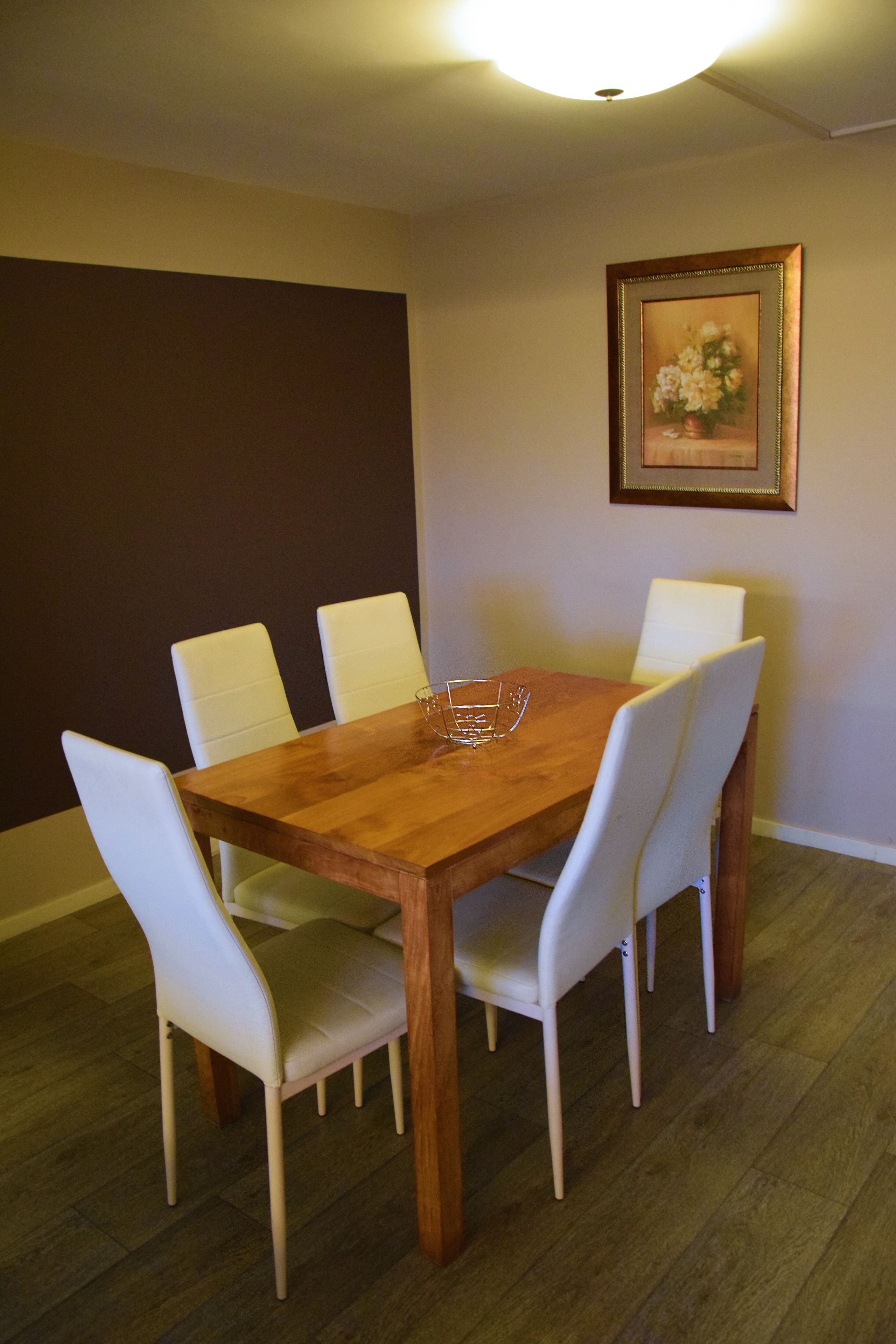 Una sala da pranzo con un tavolo di legno e sedie bianche.