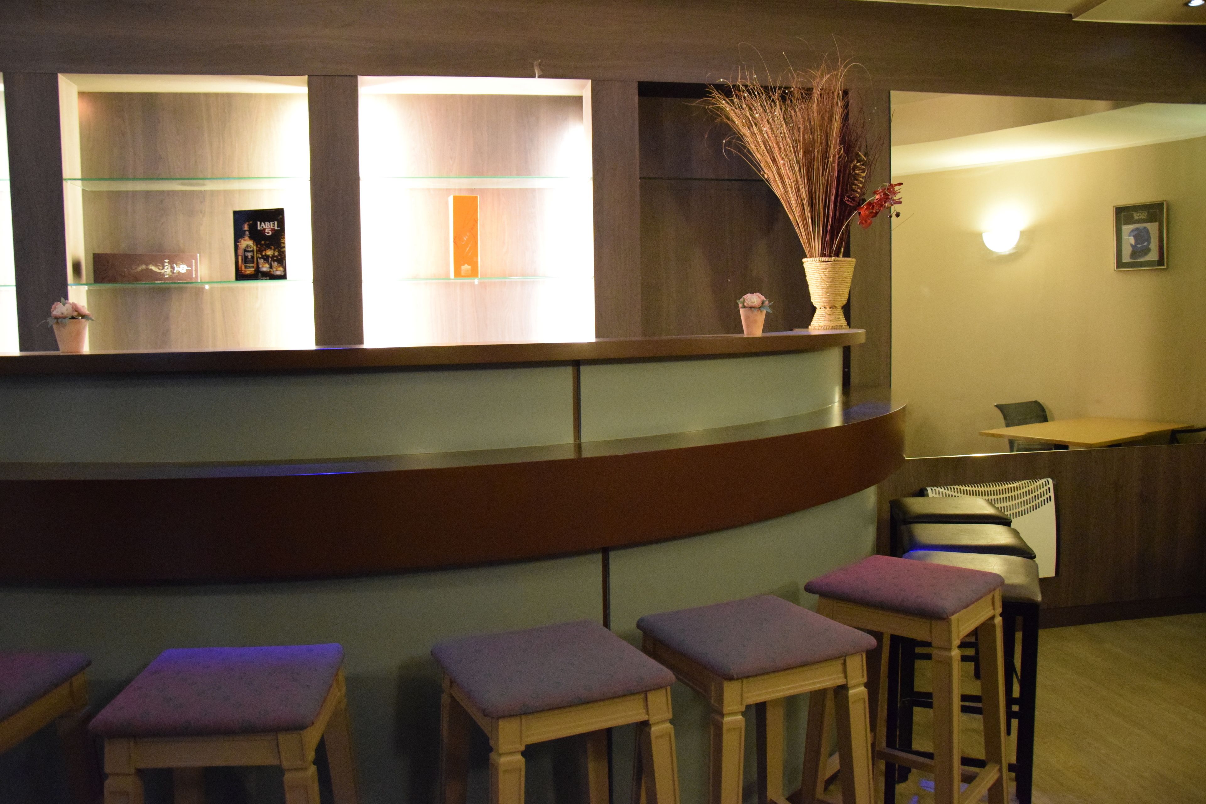 Un espace d’accueil doté d’un comptoir incurvé, d’étagères en verre et de tabourets en bois.