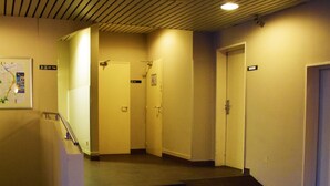 Een hotel lobby met een trap naar de bovenverdiepingen, een receptiebalie en een kaart aan de muur.