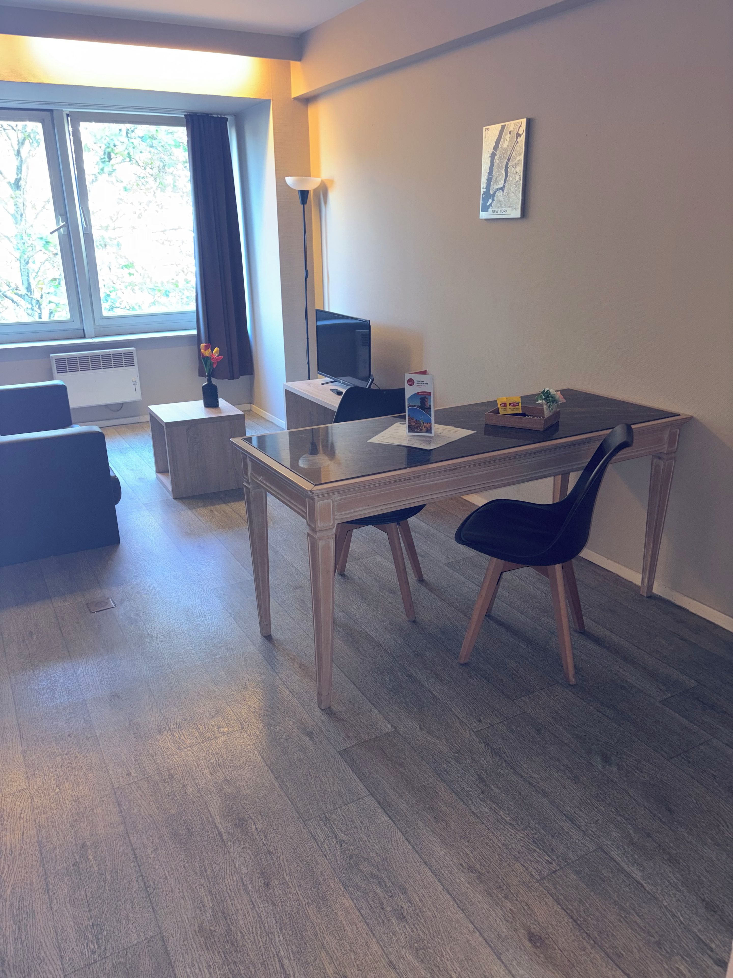 Un soggiorno moderno con un tavolo da pranzo, due sedie, un divano, una TV e una lampada.