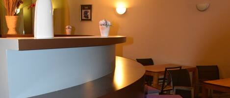 A bar area with a curved counter, bar stools, and a decorative flower arrangement.