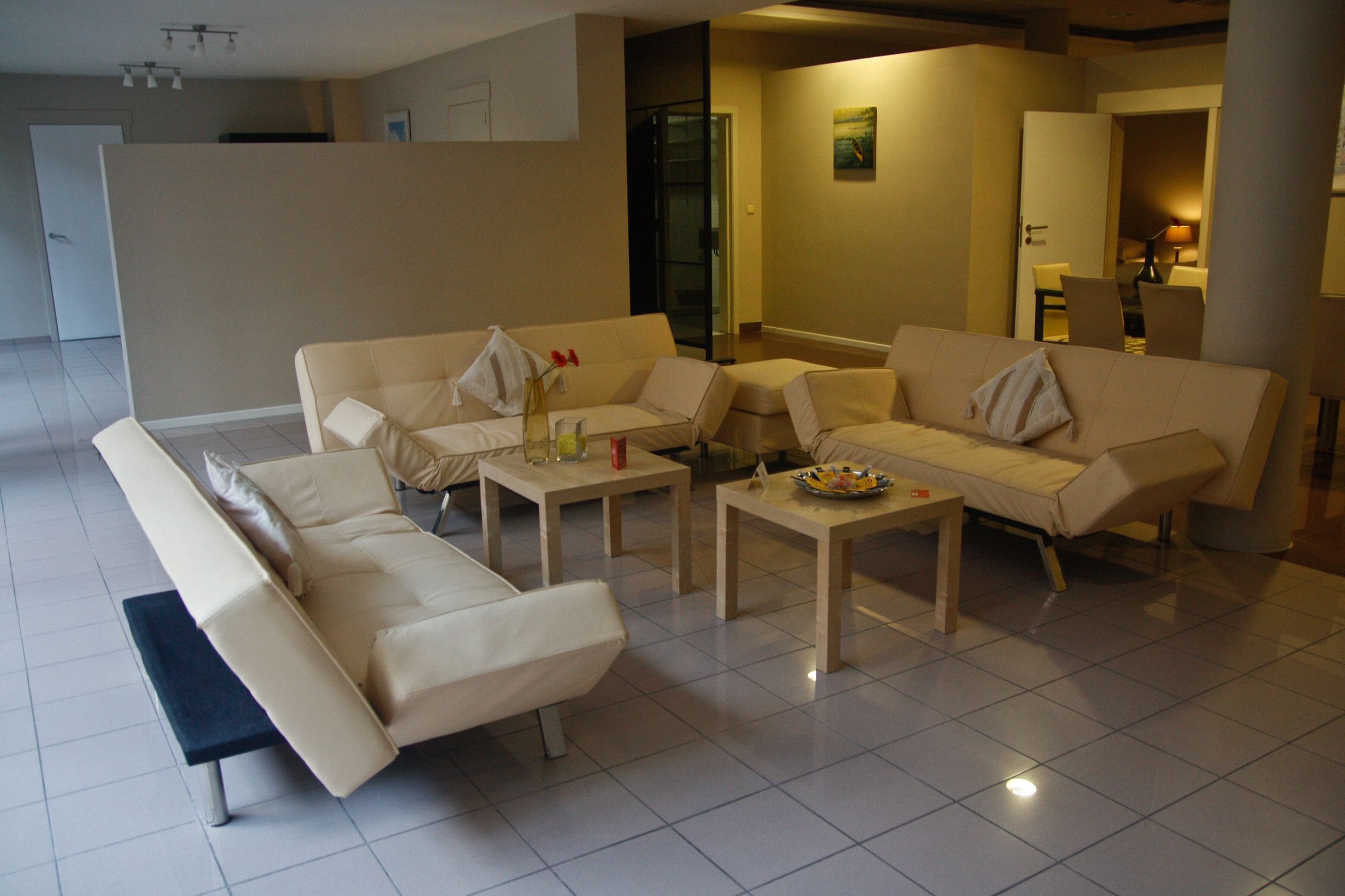A modern living room with a sofa set, coffee table, and a dining table.