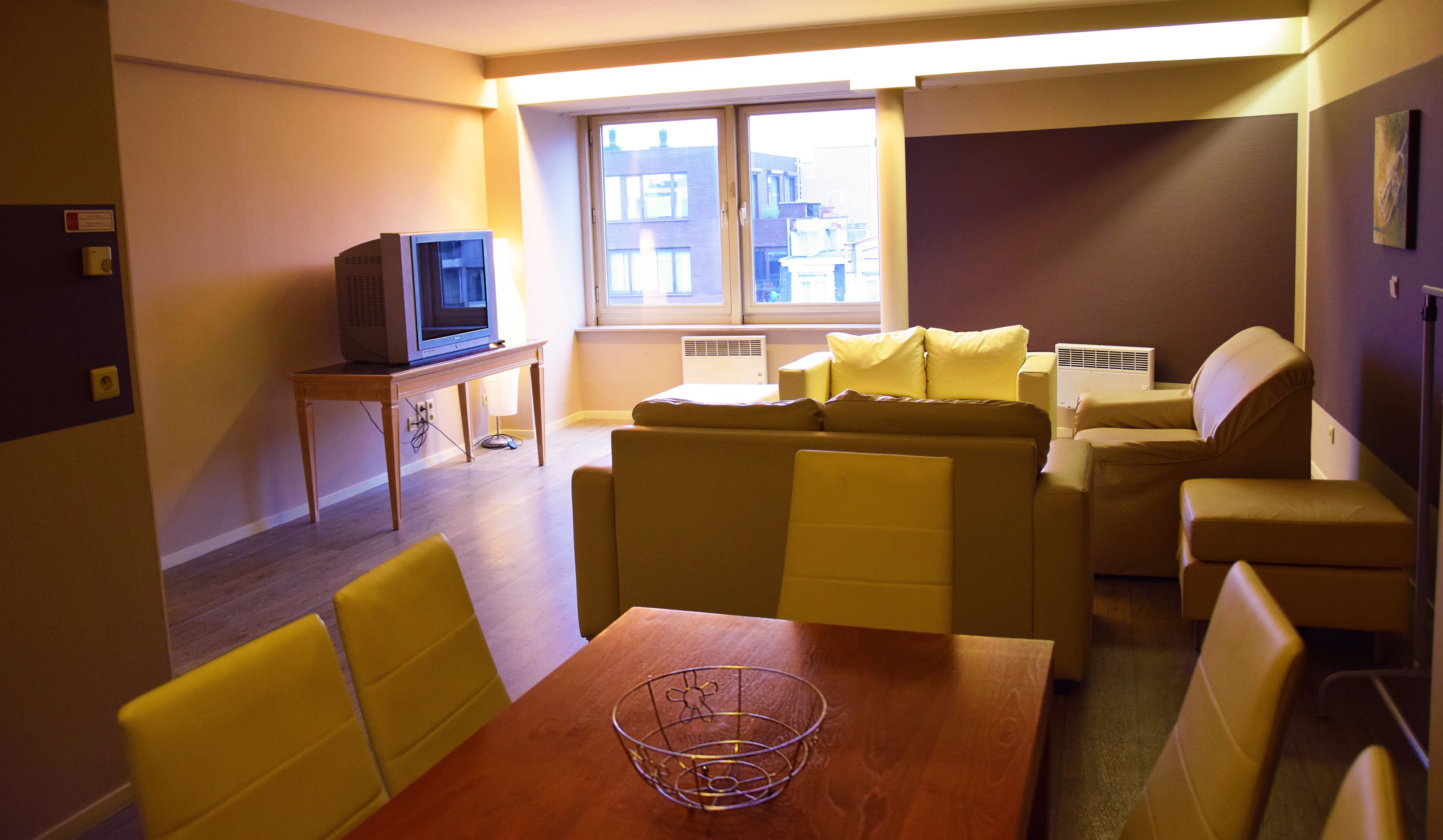 Un espace de vie compact comprenant un canapé, une petite table et un téléviseur posé sur un meuble.