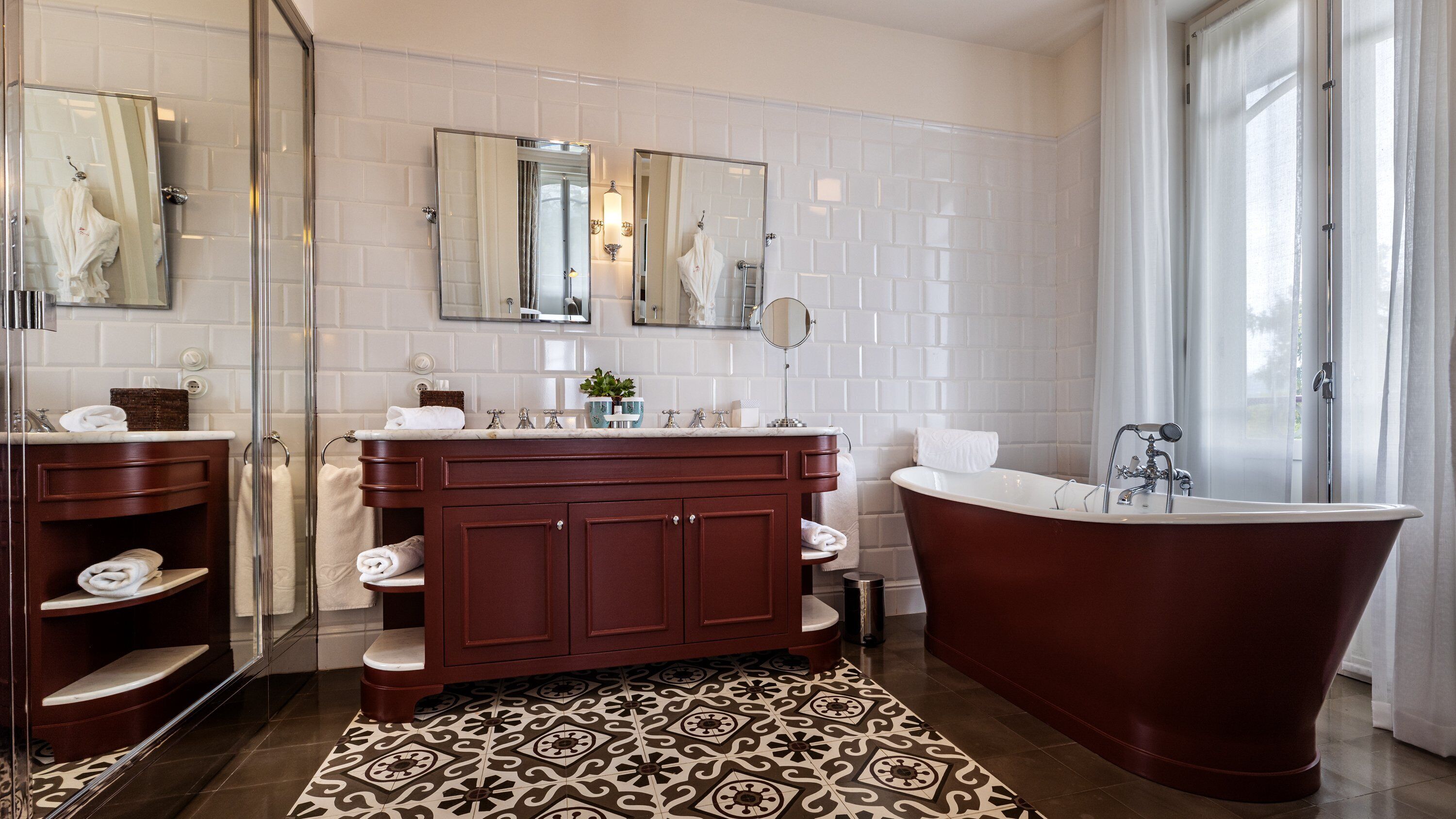A modern bathroom with a freestanding bathtub, a double vanity with a mirror, and a patterned floor.