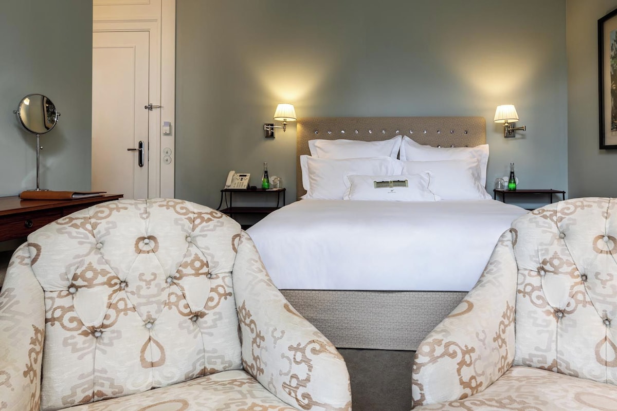 Une chambre d’hôtel avec un grand lit, deux tables de chevet, un miroir et un tableau encadré au mur.