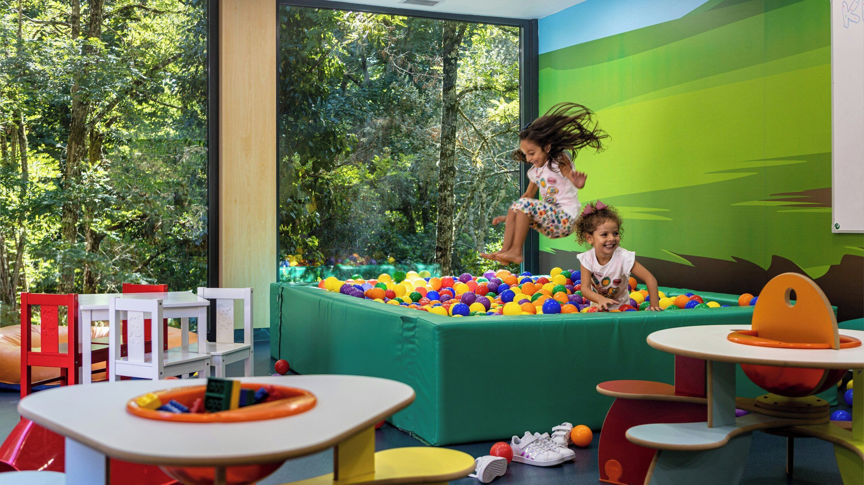 Un espace de jeux avec une piscine à balles, des tables et des chaises.