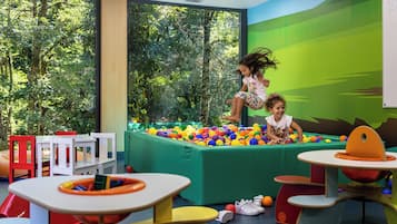 Un espace de jeux avec une piscine à balles, des tables et des chaises.