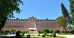 A large, multi-story building with a central fountain, surrounded by well-manicured gardens and trees. - Vidago Palace (Chaves)