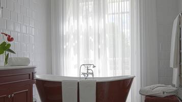 Un baño con una bañera independiente, un banco de madera, un lavabo de mármol y baldosas de suelo estampadas.