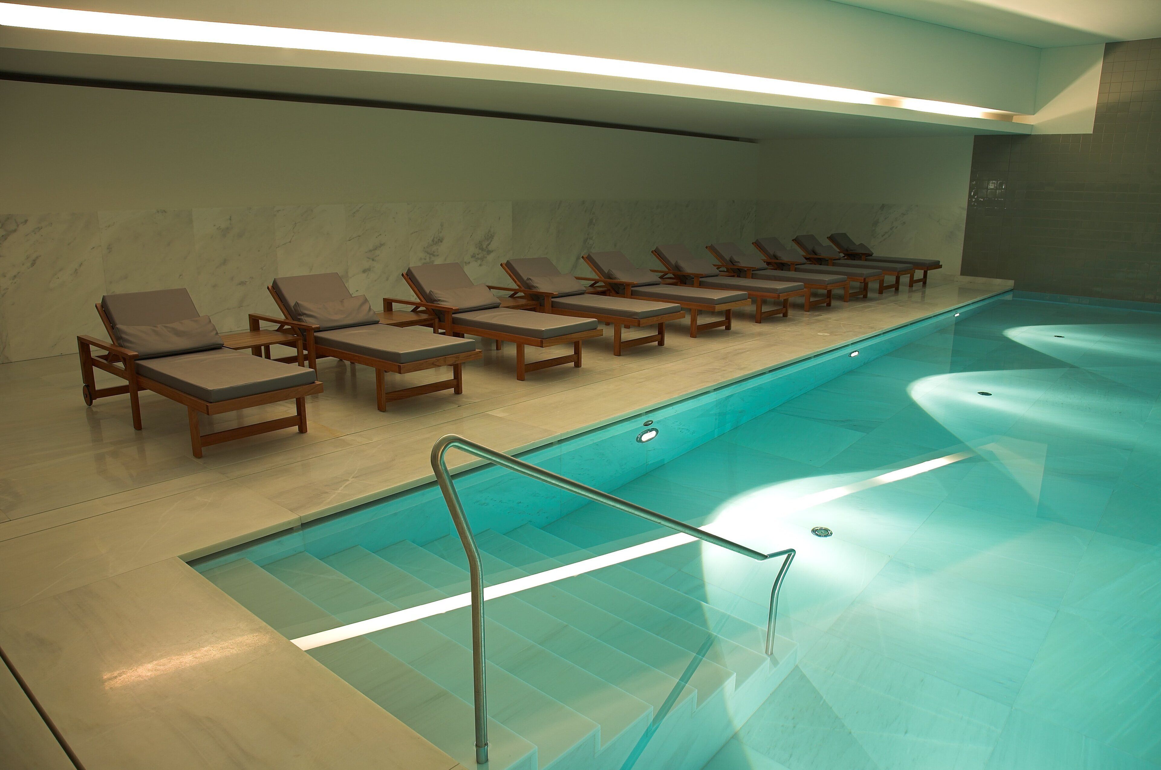 A swimming pool with sun loungers and a glass railing.