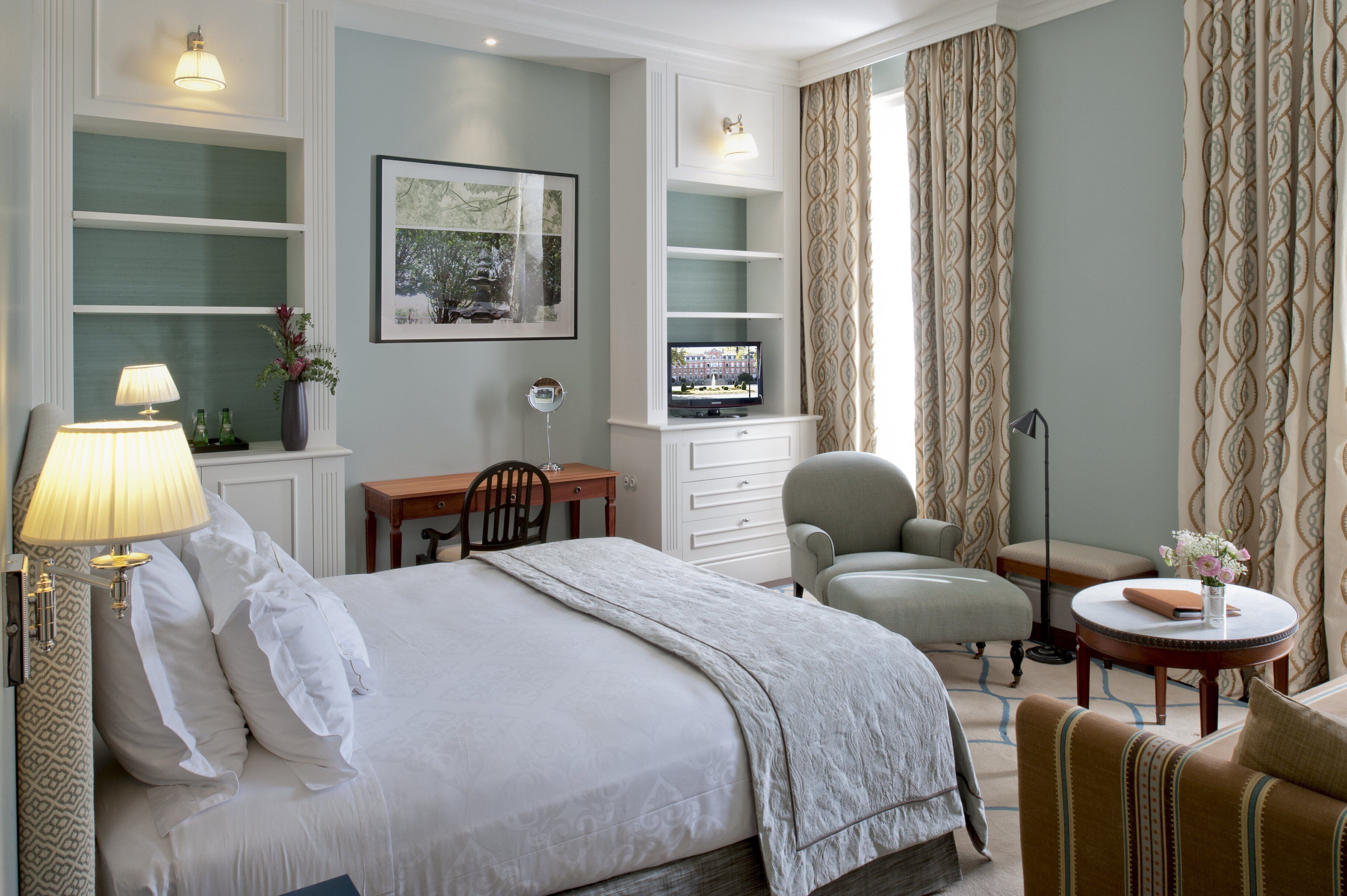 Una habitación de hotel con cama, escritorio, silla, sofá y televisor.