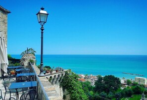 A seaside terrace with stone balustrades, outdoor seating, and a view of the ocean. - La Perla Preziosa (Grottammare)