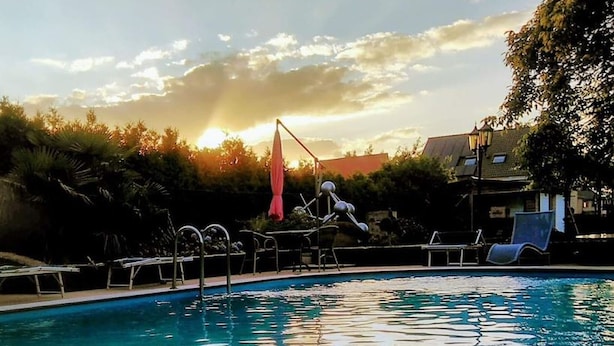 Una piscina al aire libre, sombrillas, sillones reclinables de piscina