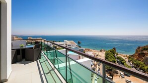 A balcony with a glass railing overlooking a coastal view, including a beach and ocean. - Villa Doris Suites (Lagos)