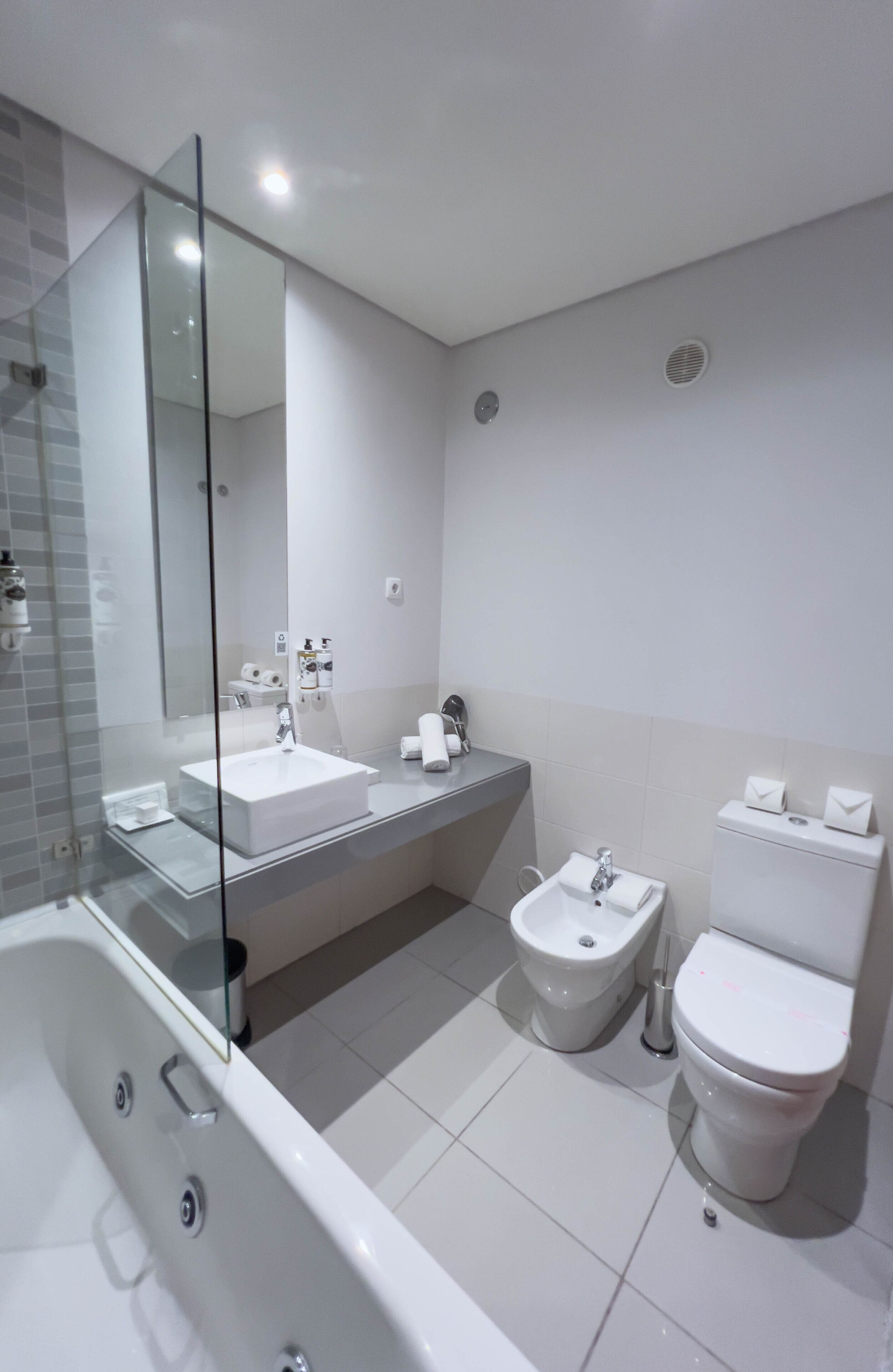 Une salle de bain moderne dotée d’une douche à parois de verre, d’un double vasque, d’un bidet et de toilettes.