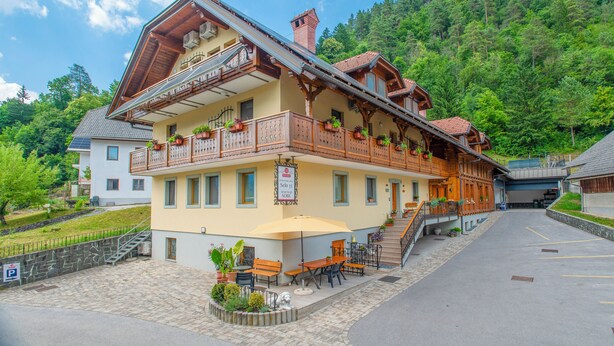 A two-story building with a balcony, outdoor seating, and a parking area. - Rooms & Apartments Pr Matjon (Bled)