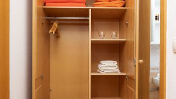 A wooden closet with shelves, a hanging rod, and a shoe rack.