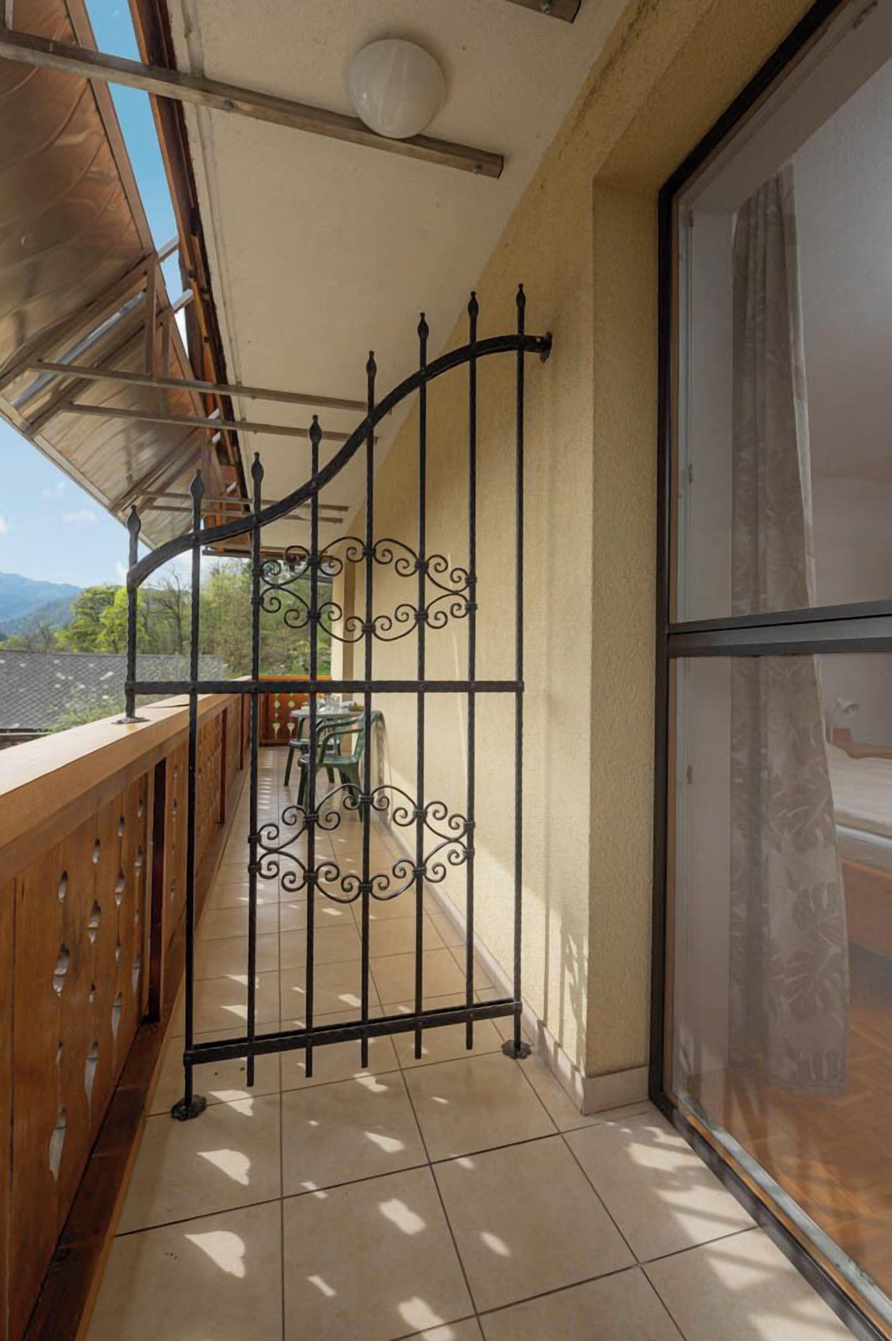 A balcony with a wrought iron gate, a wooden railing, and a view of the mountains.