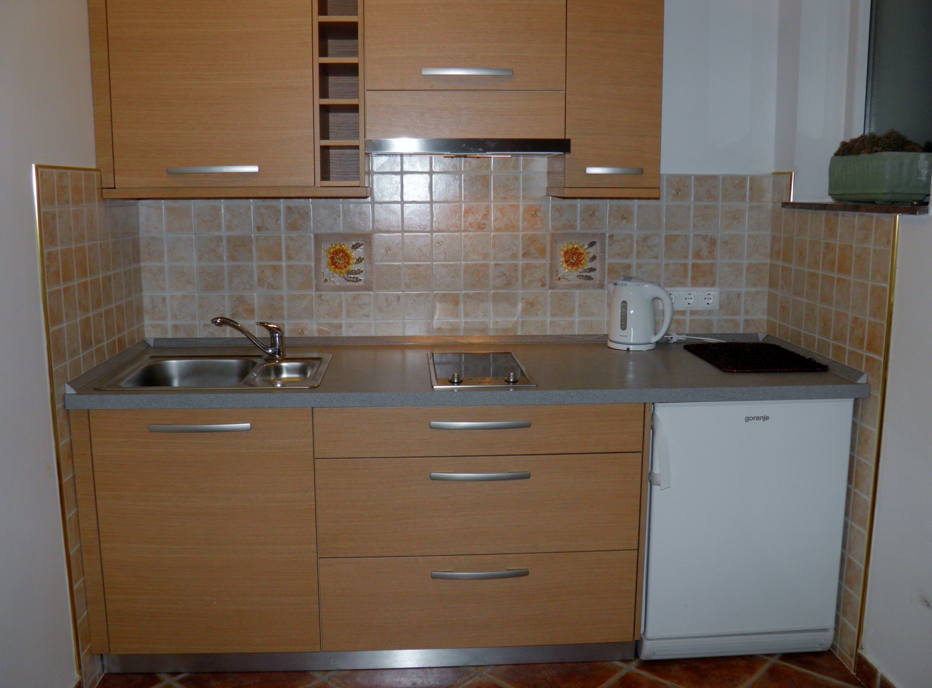 A compact kitchen with wooden cabinets, a built-in sink, a toaster, and a white refrigerator.