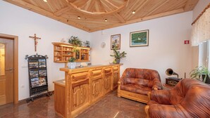 A cozy living room with a wooden ceiling, a leather armchair, a wooden cabinet, and a wall-mounted shelf with decorative items. - Rooms & Apartments Pr Matjon (Bled)