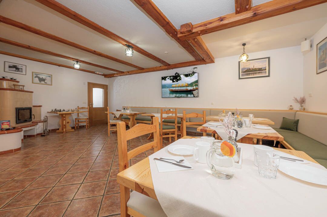 A dining area with wooden tables and chairs, a television, and a painting on the wall.