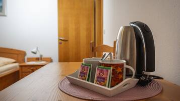 Eine Kaffeemaschine mit einer Tasse und zwei Kaffeepäckchen auf einem Tisch.