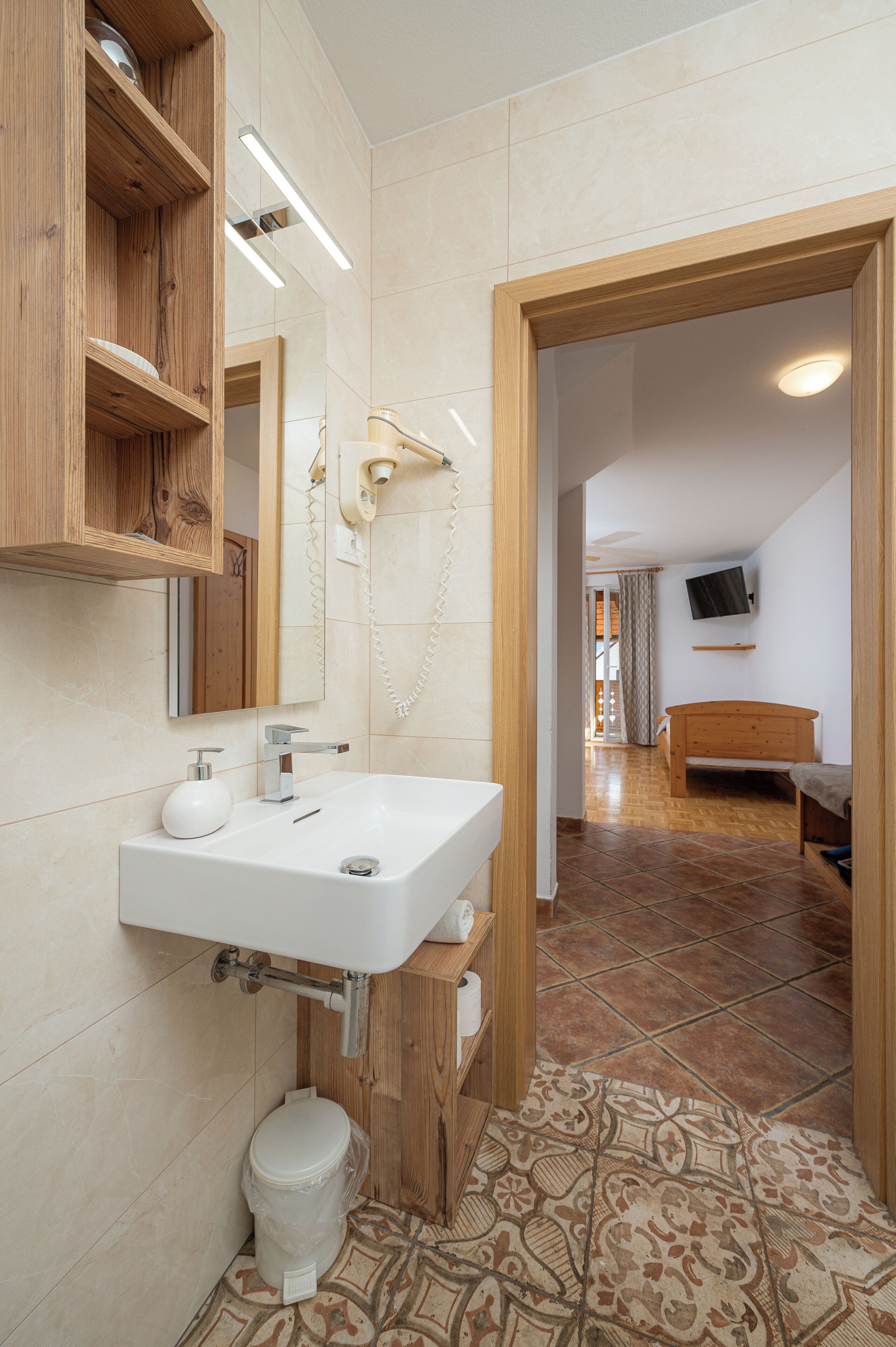 A modern bathroom with a wooden vanity, a white sink, a mirror, and a toilet.