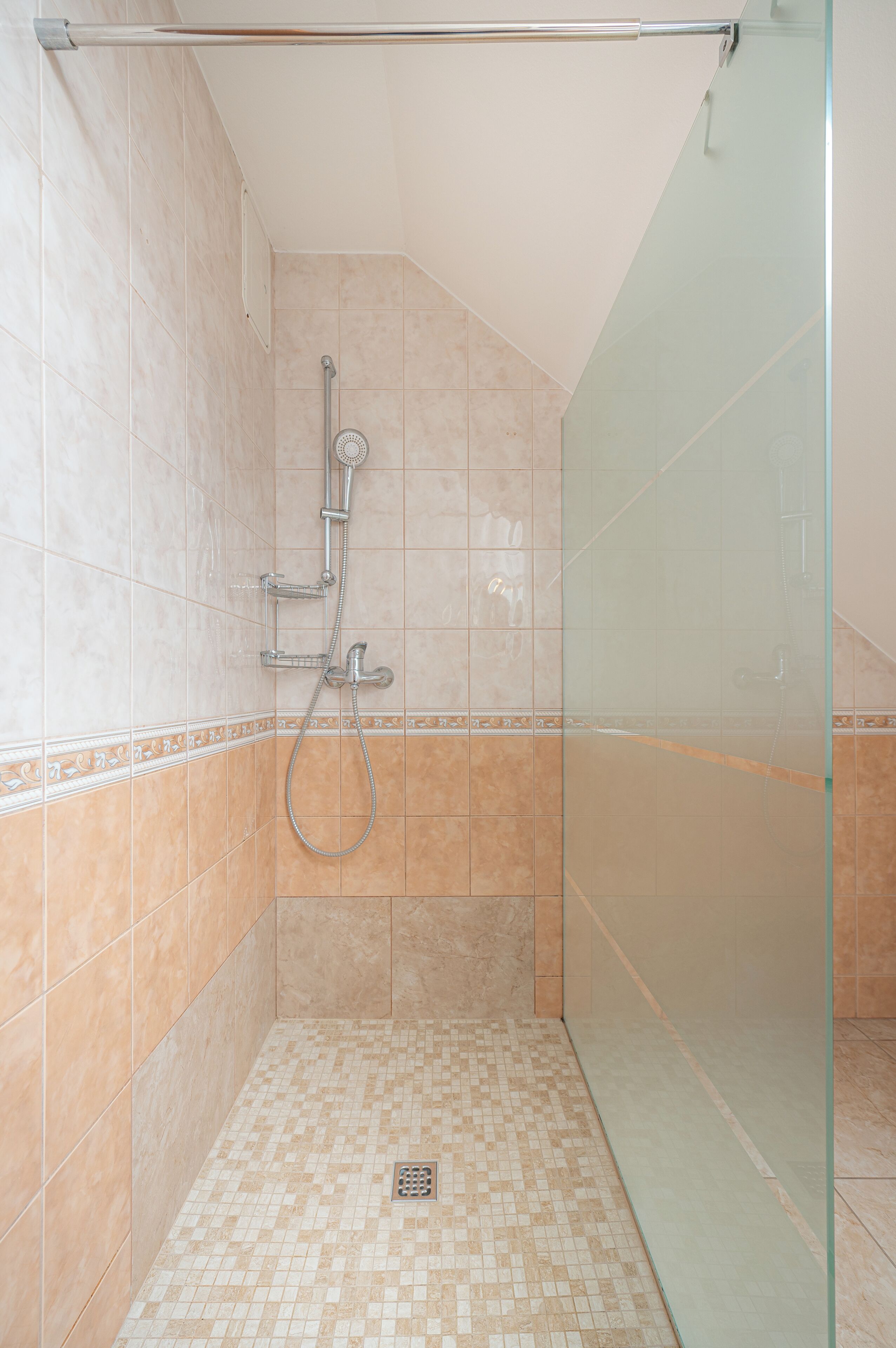 A shower area with a glass door, tiled walls, and a showerhead.