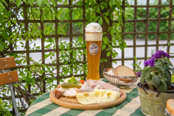 Ein Tisch mit einem Bierglas, einer Schüssel Brot und einer Platte mit Käse und Fleisch.