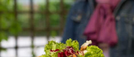 A table with a salad and a person in the background.