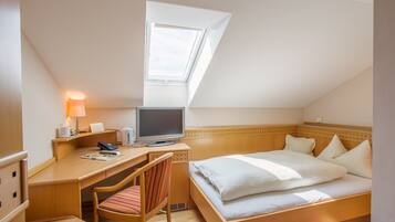 Hotellihuone, jossa on työpöytä, tuoli, sänky ja kattovalokuvio.