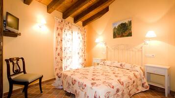 Une chambre à coucher avec un lit, une chaise, un téléviseur et un tableau accroché au mur.